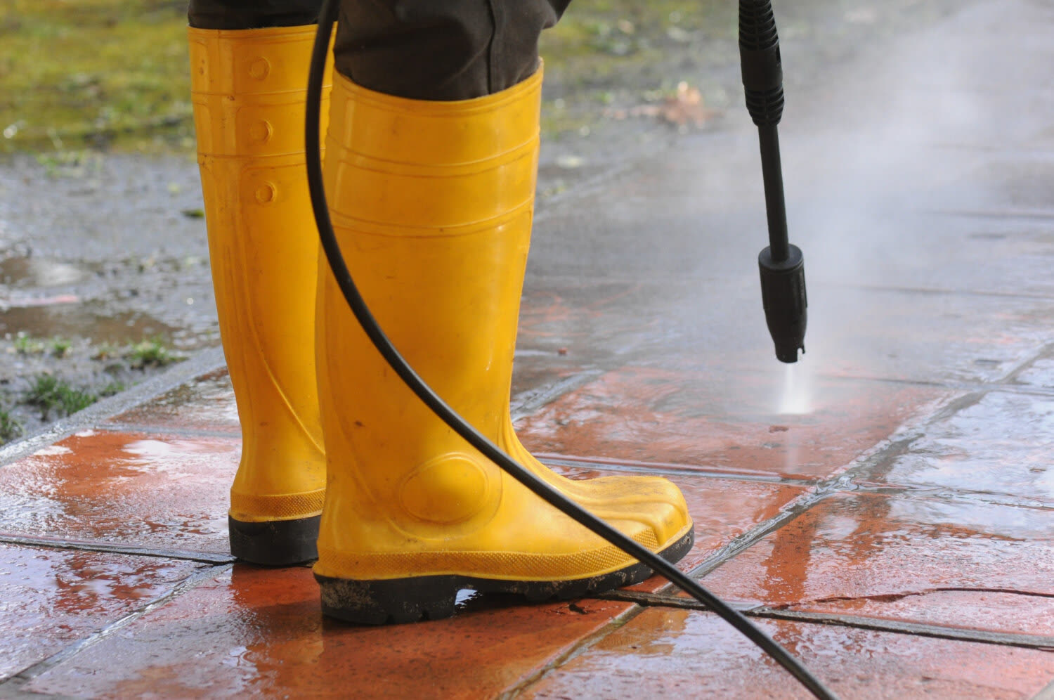 Hochdruckdüse und Gummistiefel auf einer Steinfläche