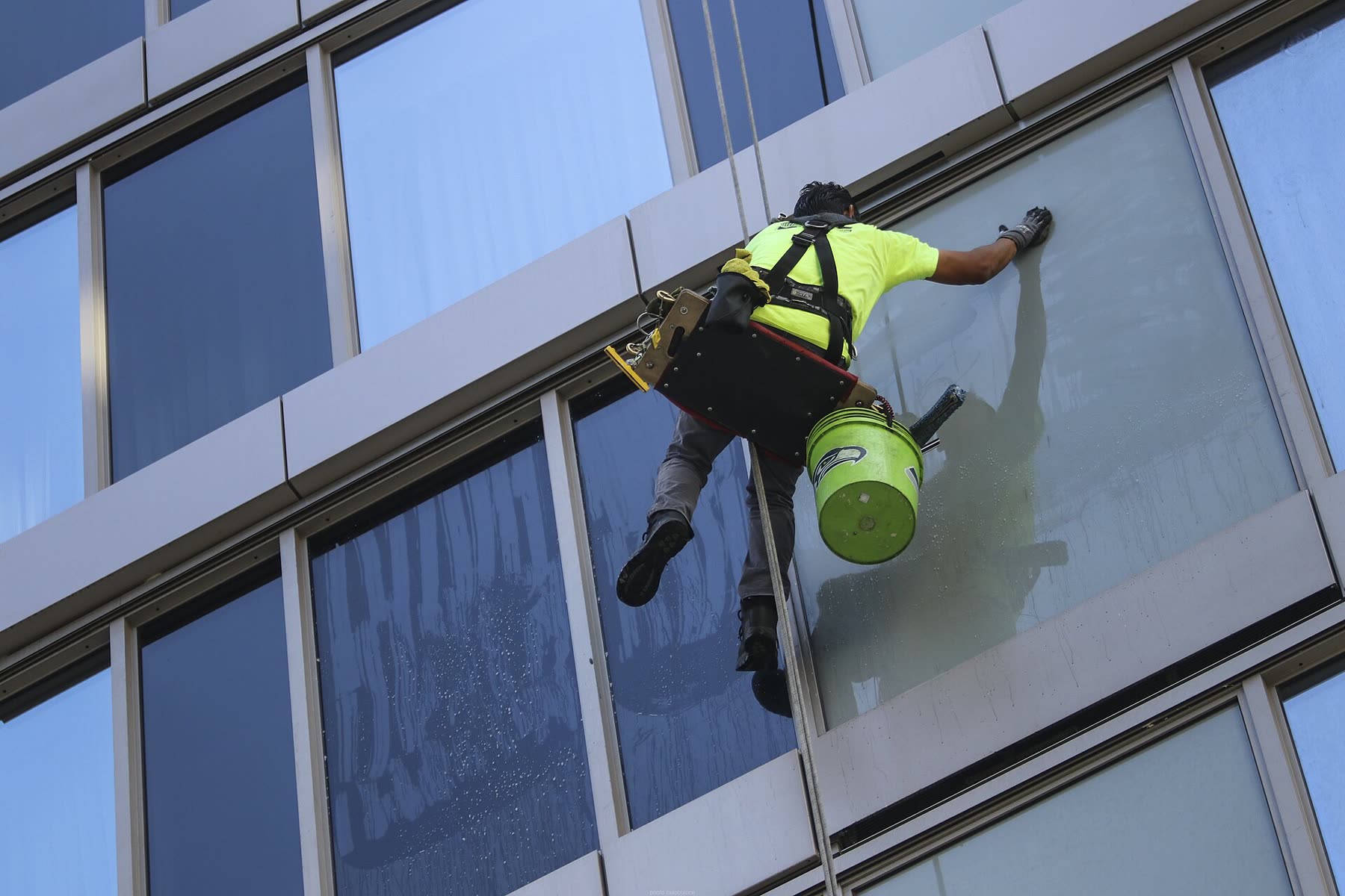 Fassadenreiniger am Seil wischt eine große Glasfassade