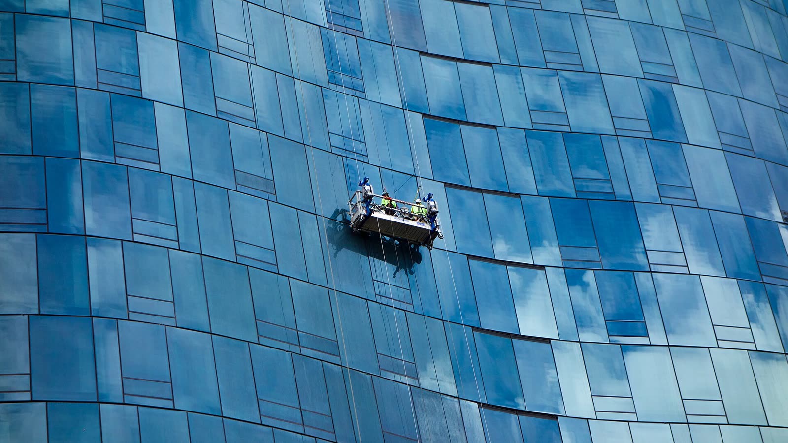 Blaue Glasfassade mit Arbeitskorb an der Außenwand